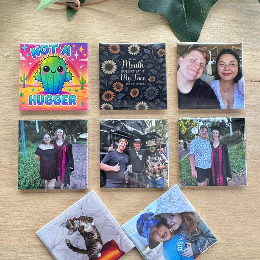 Collection of photo magnets on a wooden surface with green leaves.